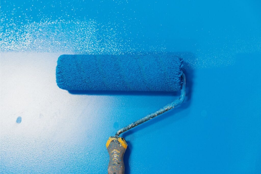 Blue paint brush on a blue wall showing the commercial painting service offered by Michael Grant Painting.